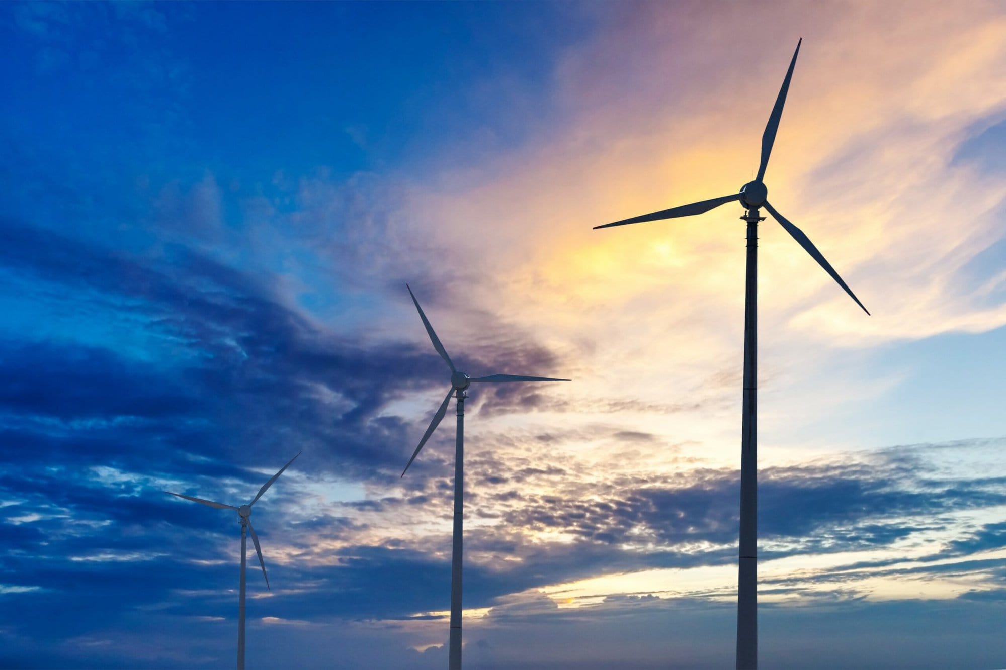 Green renewable energy concept - wind generator turbines sihouettes on sunset
